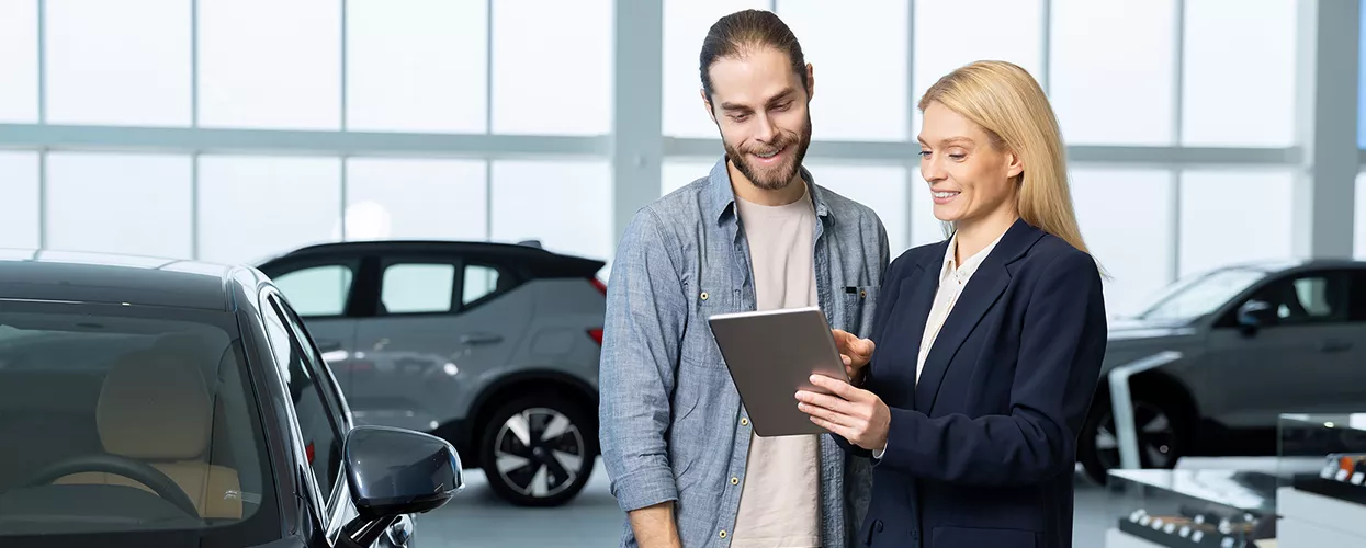Car salesman showing a customer a tablet in a car dealership