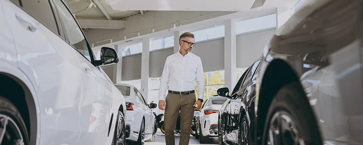 a person at a dealership looking at cars in showroom