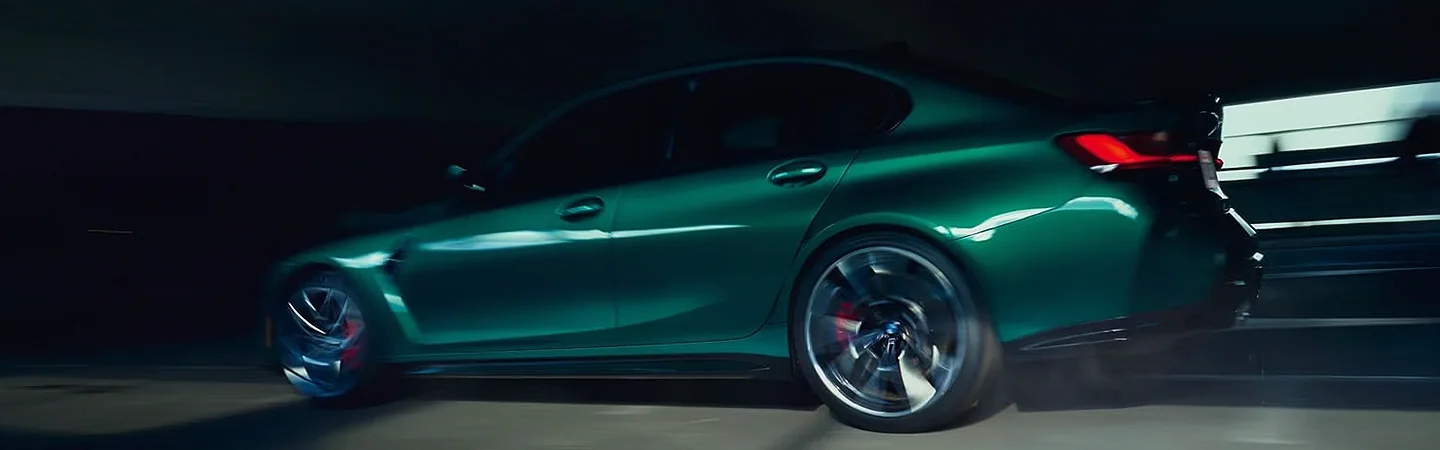 Side view of a green 2024 BMW M3 driving