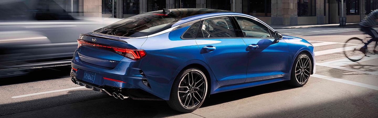 Blue 2021 Kia K5 stopped at a crosswalk