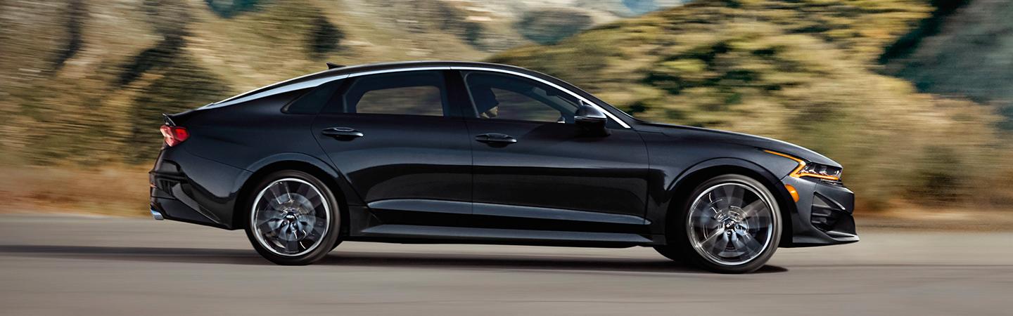 Side view of the black 2021 Kia K5 in motion