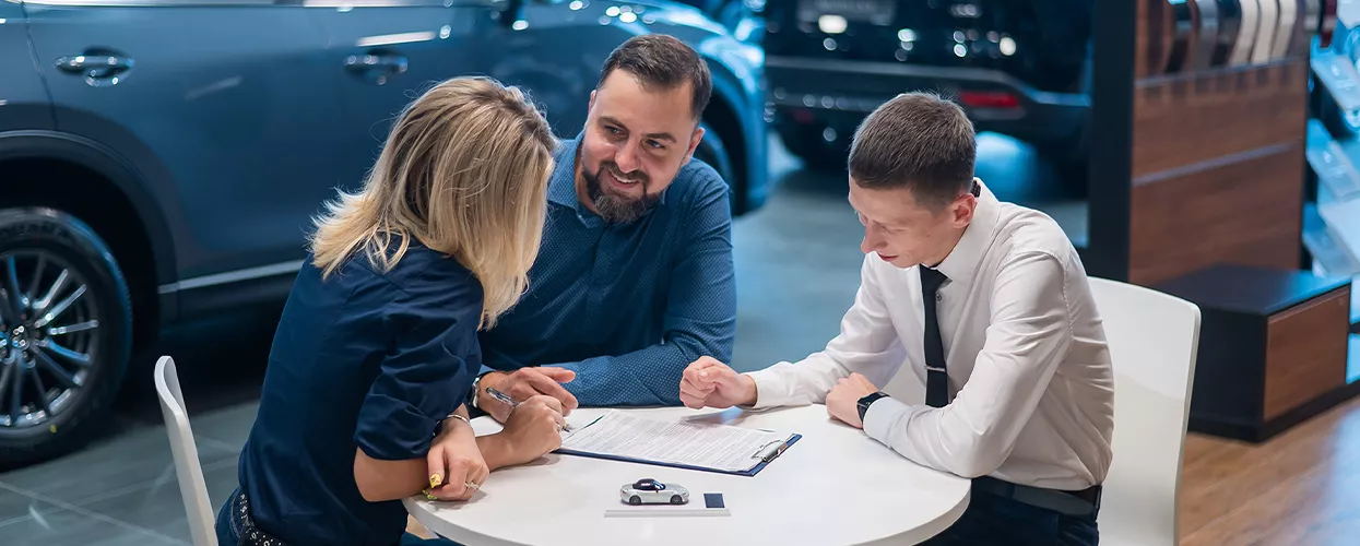 Customer reviewing BMW finance and lease paperwork with an advisor at a dealership