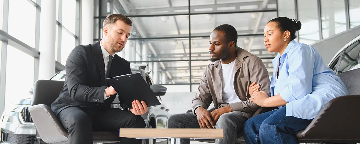 Couple talking to a car salesman about a contract