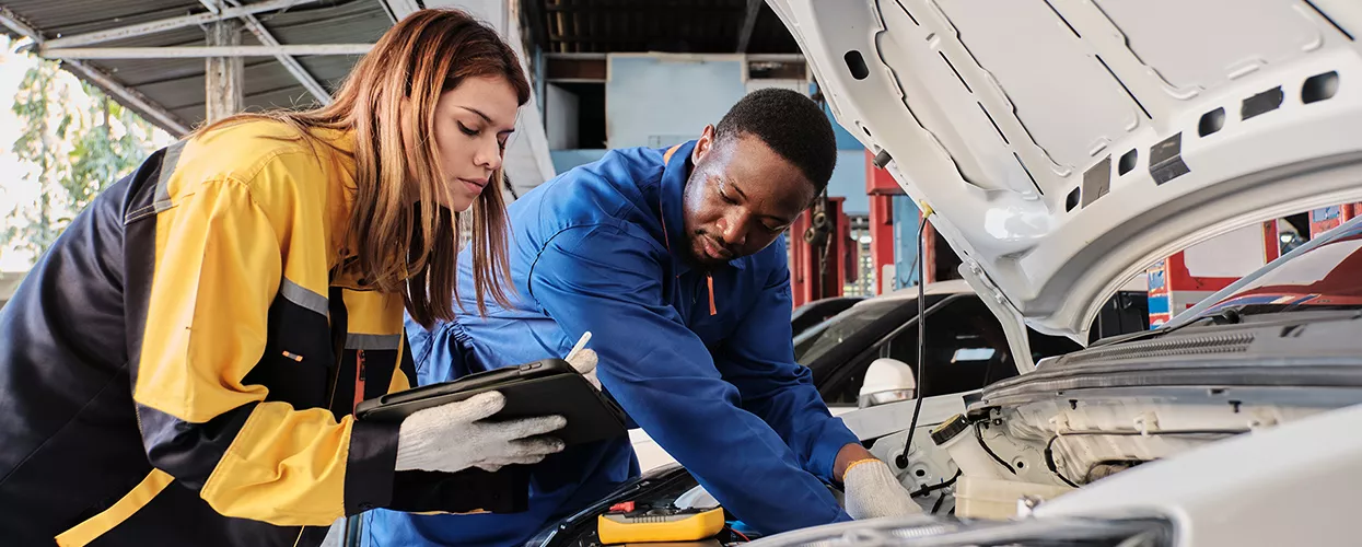 Service mechanics working under the hood of a vehicle