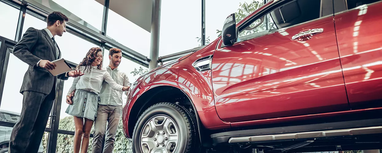Car salesman talking to a couple about a new vehicle
