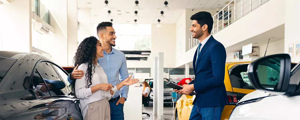 a couple speaking with car salesperson at a dealership