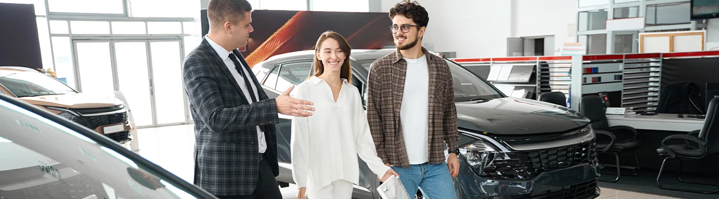 Sales person walking thougha  show room with customers talking about used vehicles