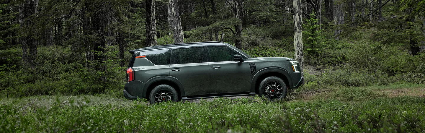 Side view of a green 2026 Nissan Armada parked on a wooded trail