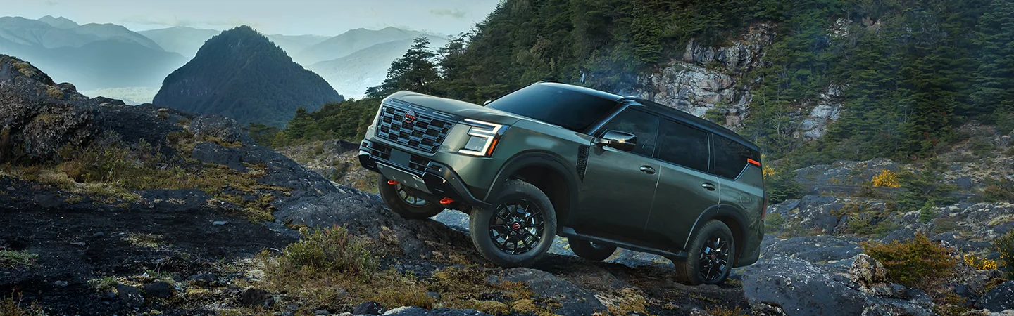 Side view of a green 2026 Nissan Armada parked on rocky area