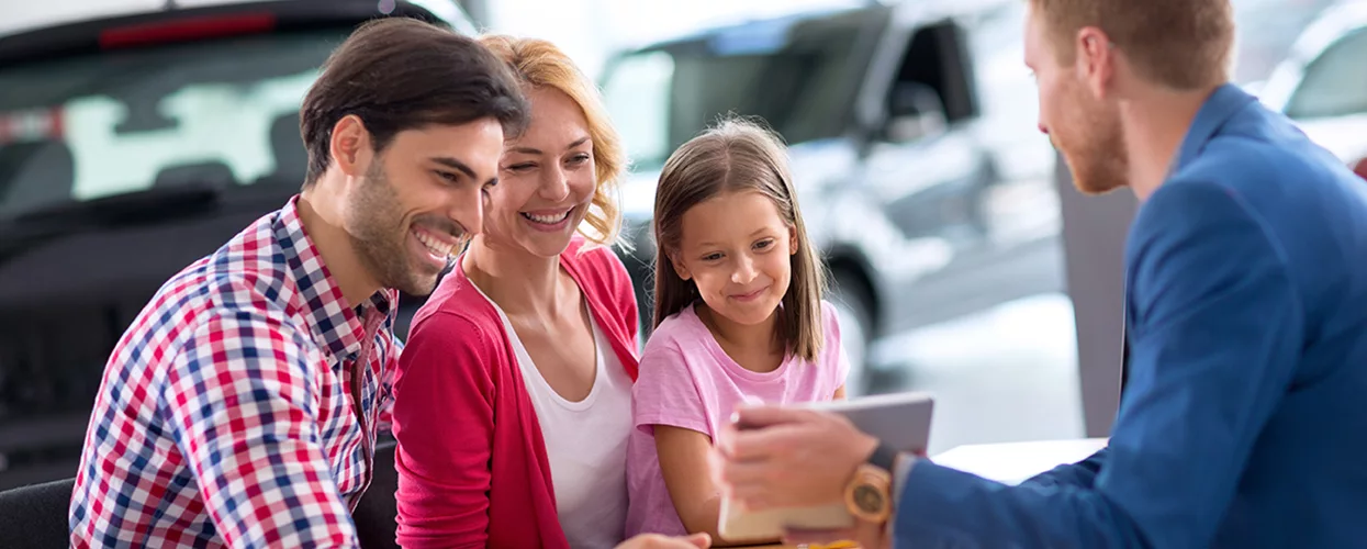 Family talking to a car salesman about a contract