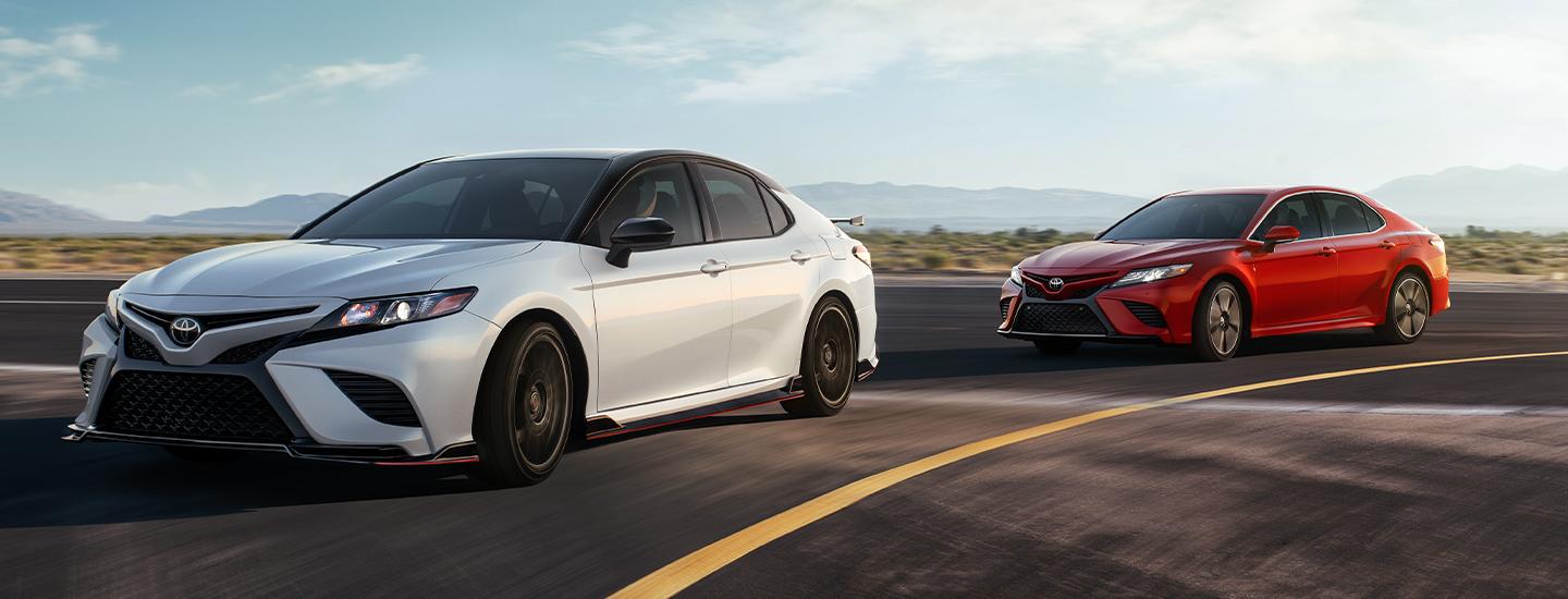 White and Red 2020 Toyota Camrys Turning on Road