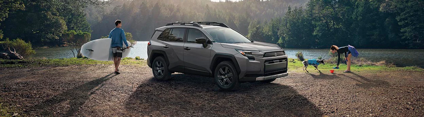 A parked 2025 Toyota RAV4 at a lake with a family playing by the lake