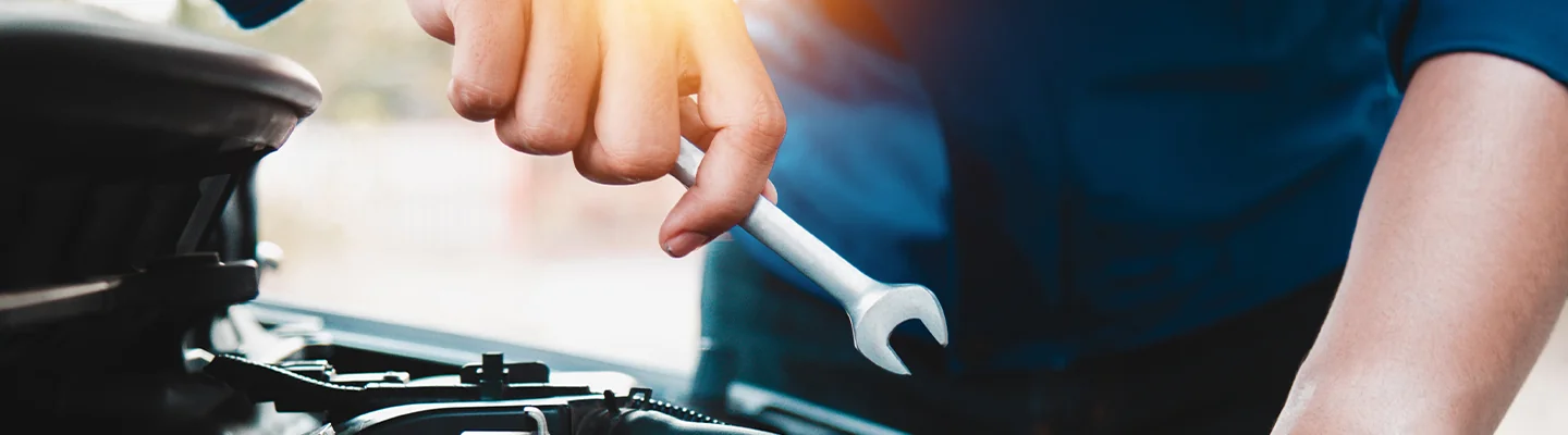 auto mechanic hand with a wrench working on car