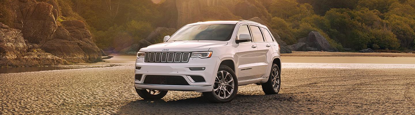 Angled profile of a parked white Jeep Grand Cherokee