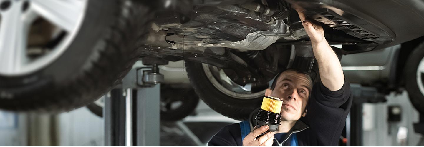 A service technician working under a lifted vehicle