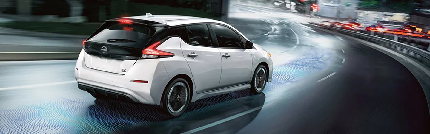 Back view of a white 2025 Nissan Leaf driving on the read