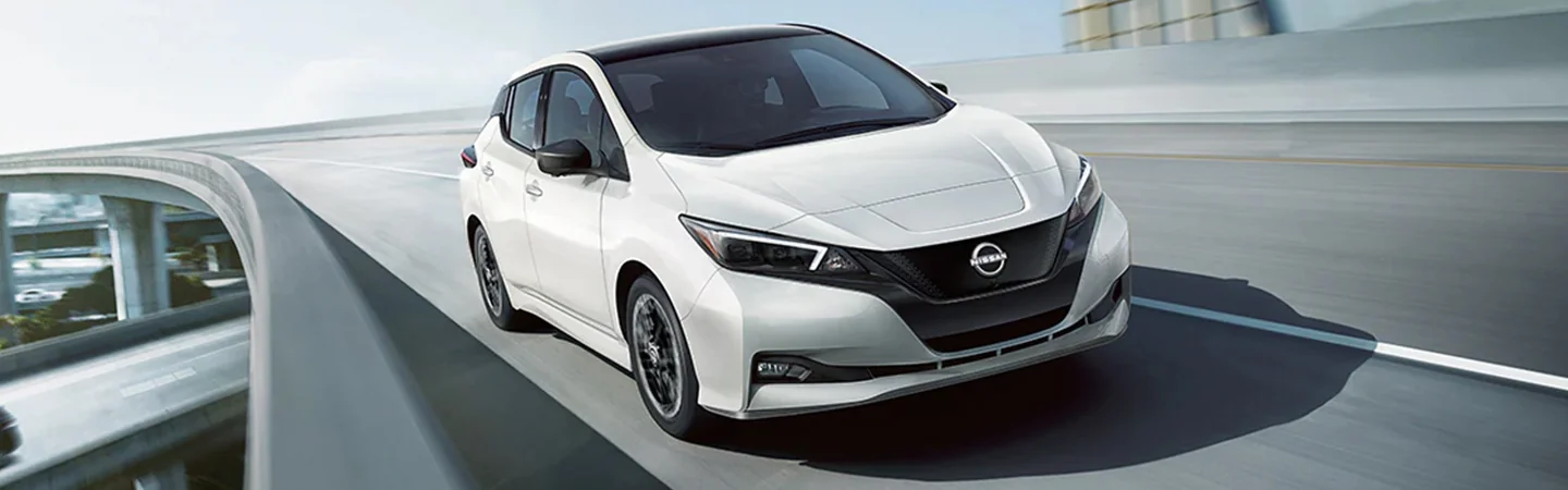 Front view of a white 2025 Nissan Leaf driving on the freeway