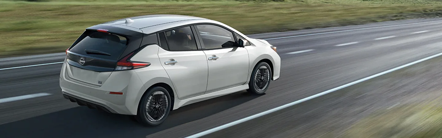 Side view of a white 2025 Nissan Leaf driving on the road