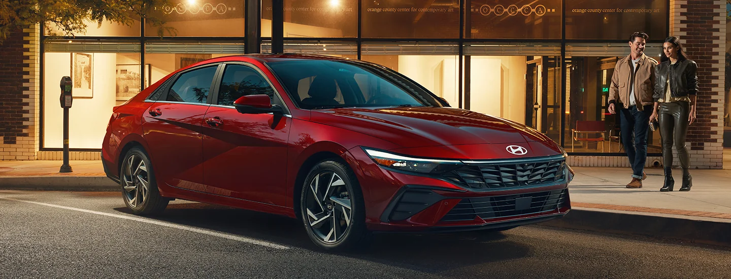 red 2025 Hyundai Elantra SE parked in city with couple approaching