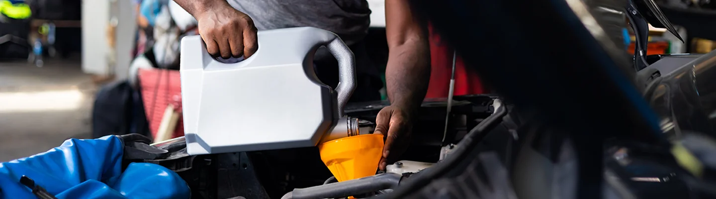 mechanic pouring oil into the engine with a funnel