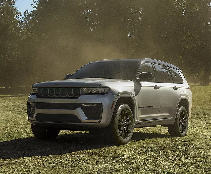 A gray 2027 Jeep Grand Cherokee parked in a grass lawn