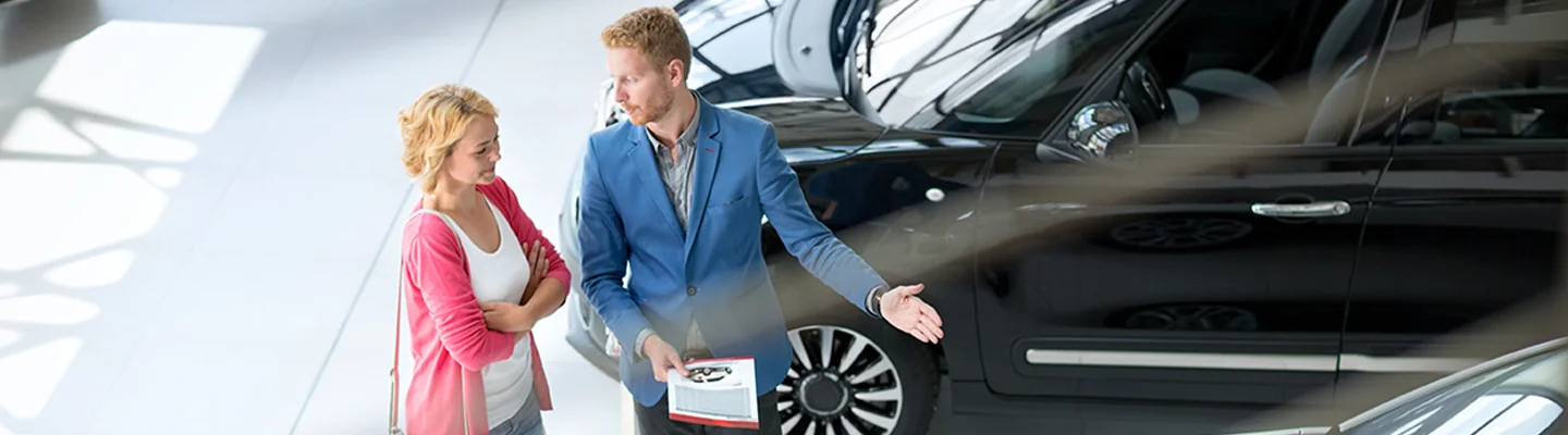 Sales person holding paperwork about the new commercial car they are looking to buy