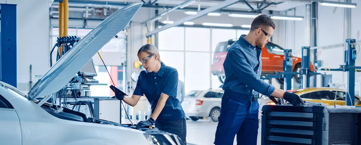 BMW technician performing routine maintenance in a service bay
