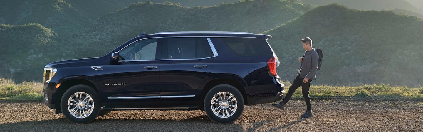 2021 GMC Yukon parked in mountains with Man using foot switch to open rear