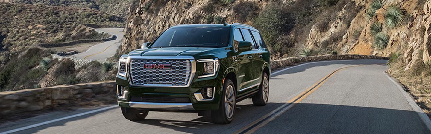 Front view of a 2021 GMC Yukon driving on a mountain road