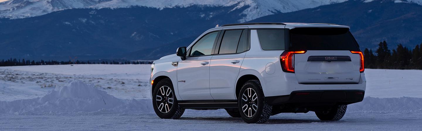 White 2021 GMC Yukon parked in snowy area with view of mountains