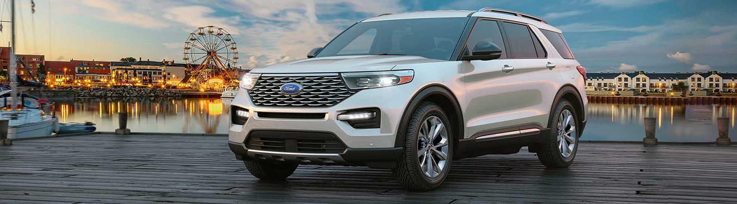 White Ford Explorer parked on a dock with a ferris wheel pier in background