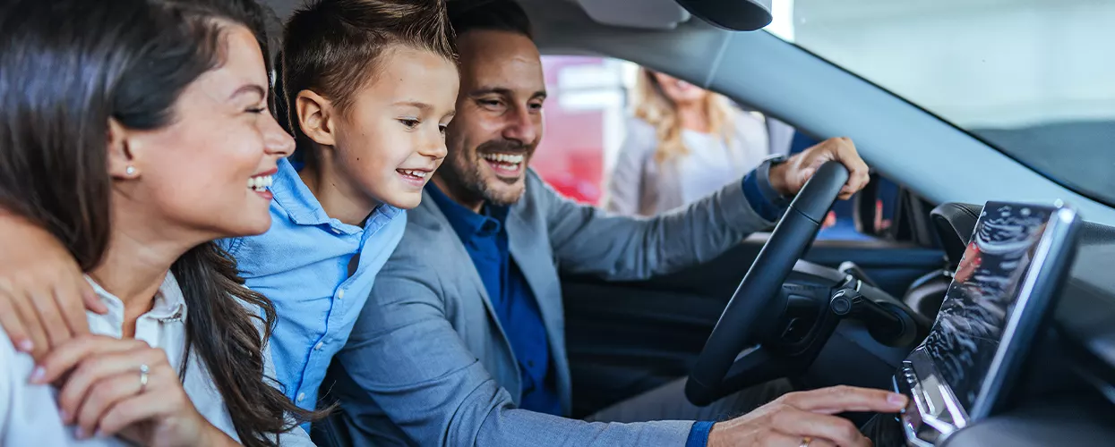 Family sitting in a new vehicle at a car dealership