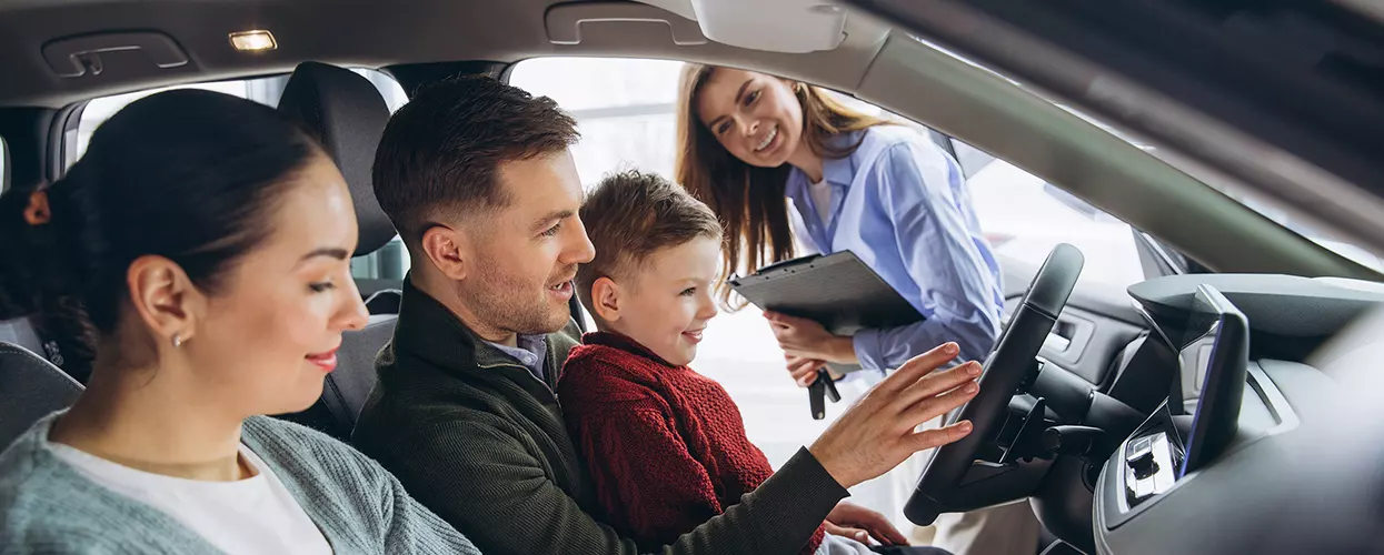 Family sitting in a new vehicle at a car dealership