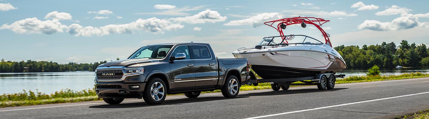 2021 RAM 1500 in motion towing a boat side view
