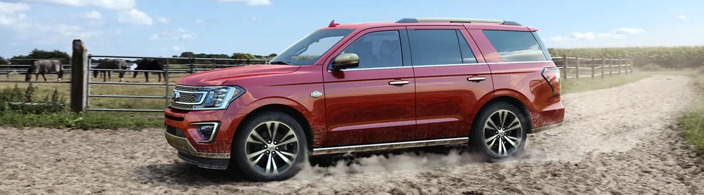 2021 Crimson Red Ford Explorer tearing up a dirt road near a farm