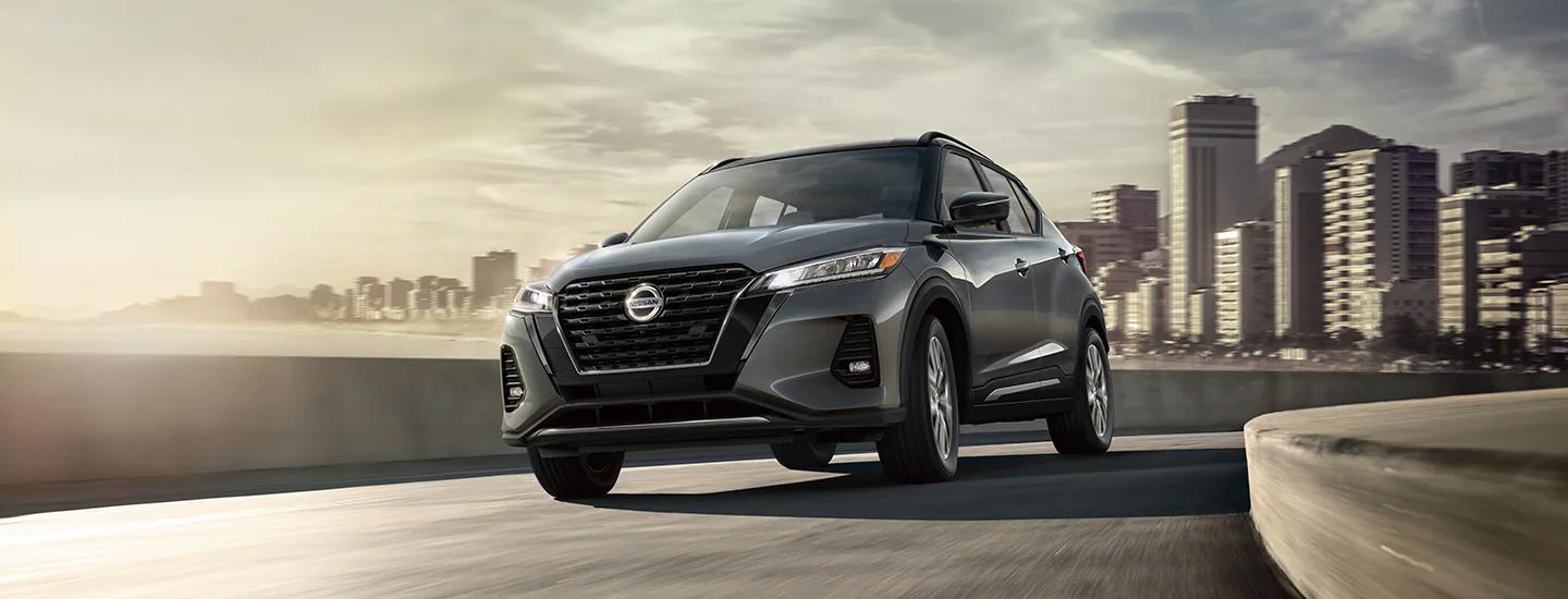 Gray 2021 Nissan Kicks driving with city in the background