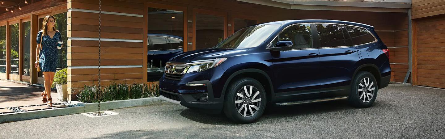 2022 Honda Pilot parked side view with woman holding coffee walking nearby