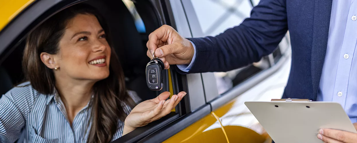 Happy women receiving keys to her new car