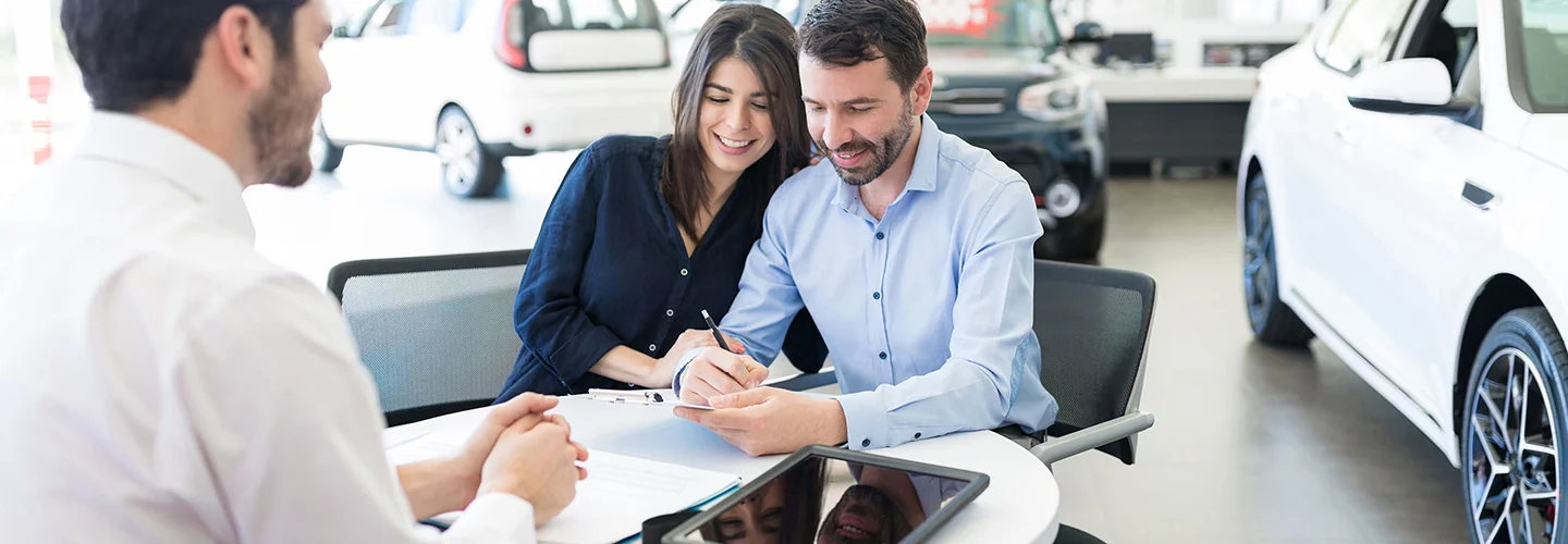 two happy people talking with car salesperson in the showroom about to purchase car