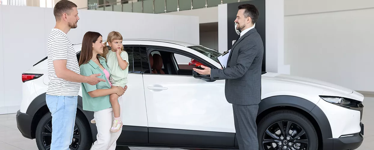 family of 3 speaking with car salesperson at dealership