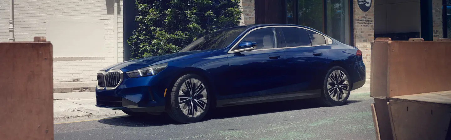 A blue 2025 BMW 5 Series parked on the street
