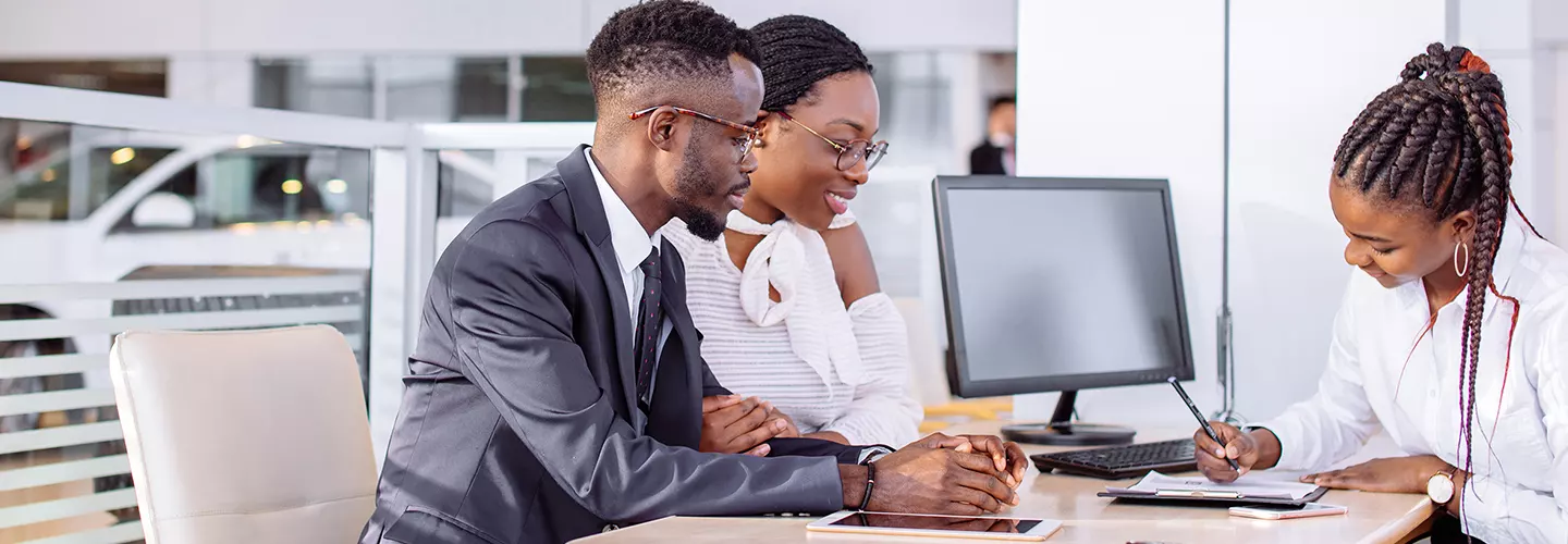 Car salesman walking a couple through a contract