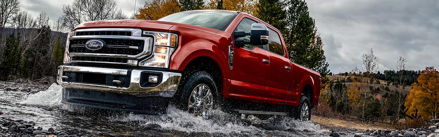 A red Ford Super Duty truck driving through water