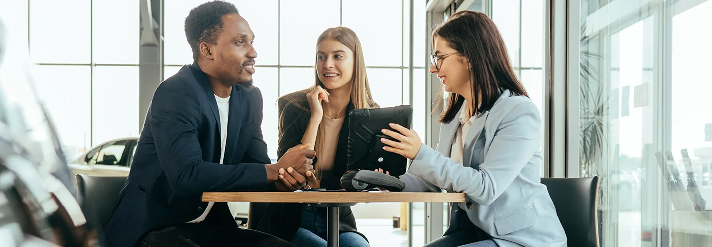 couple speaking with car salesperson in dealership