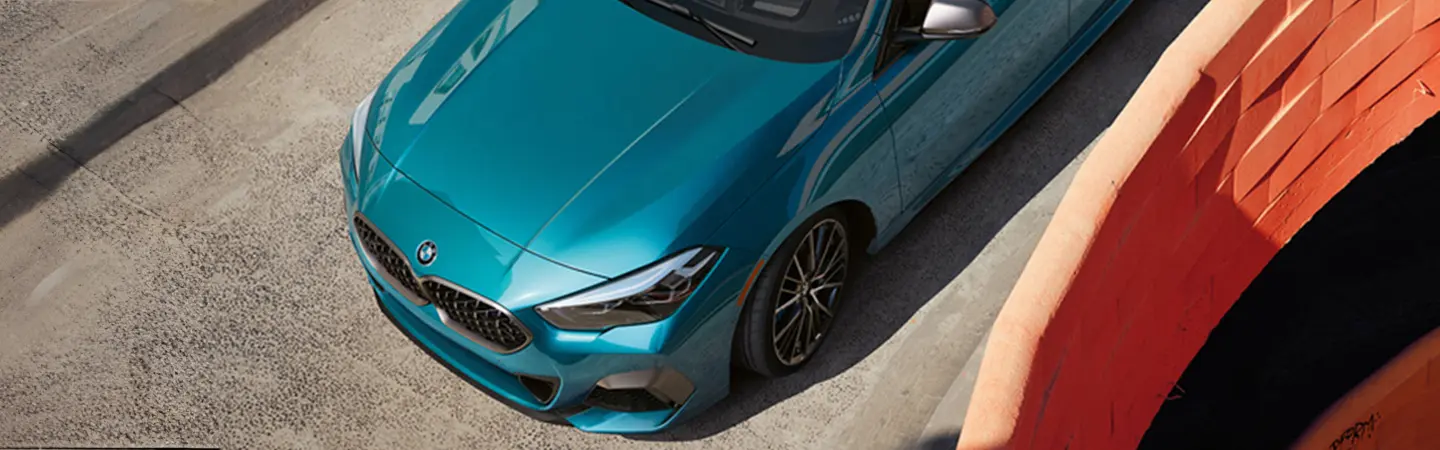 Front side view of a red 2025 BMW 2 Series driving in the city