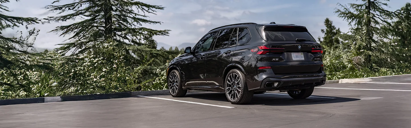 2026 BMW X5 parked in a wooded parking area