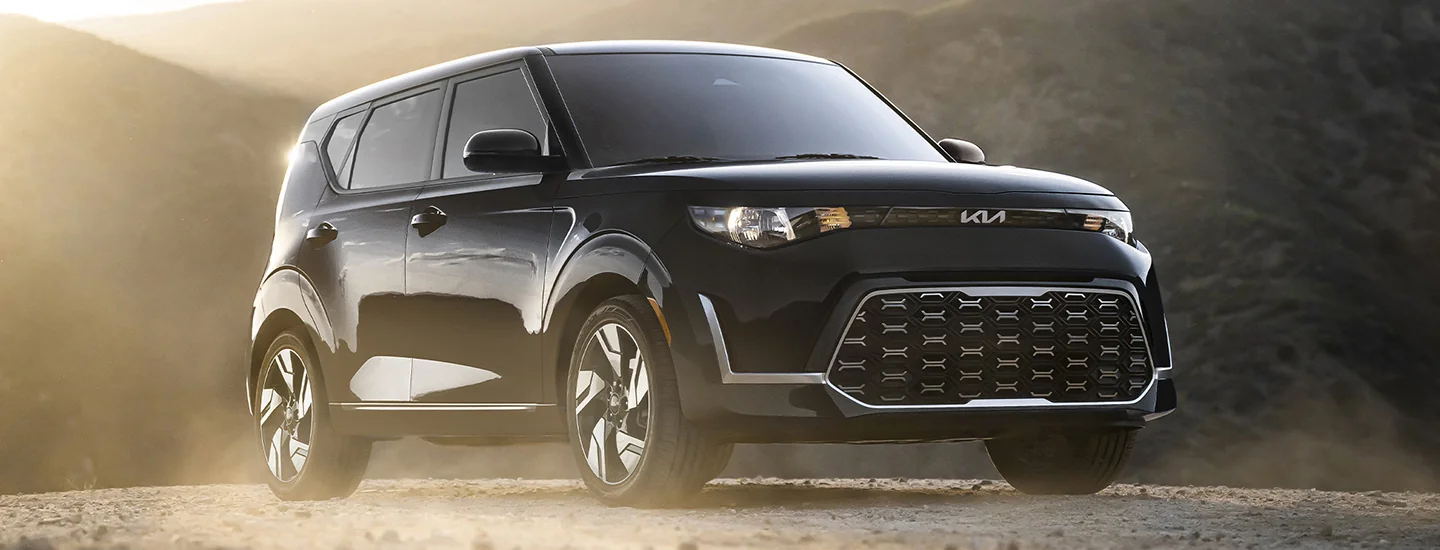Front side view of a black 2025 Kia Soul parked in the wilderness