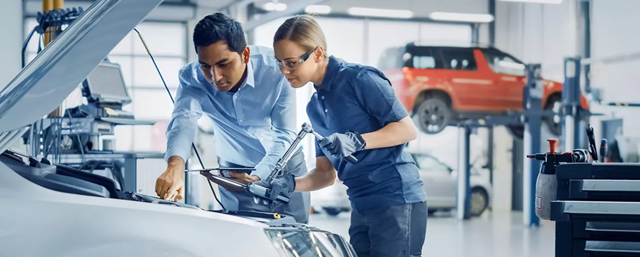 Service mechanics working under the hood of a vehicle
