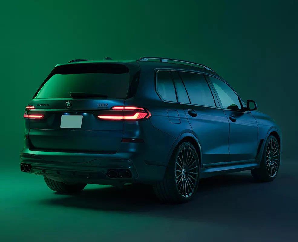Back side view of a parked green blue 2027 BMW X7 in a green room