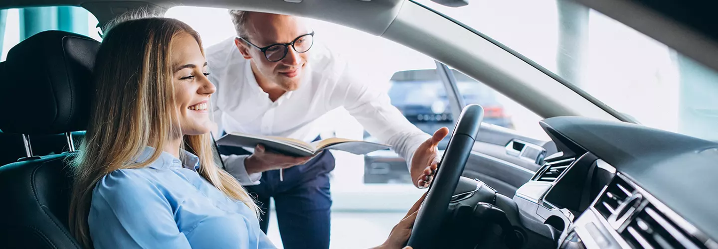 Car salesman showing a woman the interior of a new vehicle